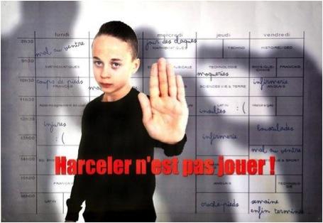 Un jeune garçon vu en buste et vêtu de noir, tend en avant la main gauche qui apparaît en gros plan. En rouge le slogan &quot;Harceler n&#039;est pas jouer!&quot; 